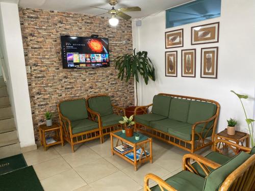 sala de estar con 2 sillas y TV en Hostal Casa Latina en Manta