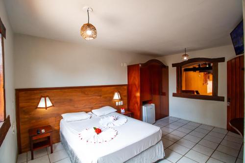 a bedroom with a bed with white sheets and flowers on it at Village Arraial BY MN Hoteis in Arraial d'Ajuda