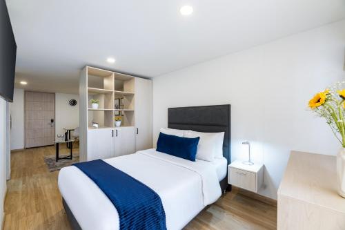 a bedroom with a large white bed with blue accents at Torre Ventto Lofts in Bogotá