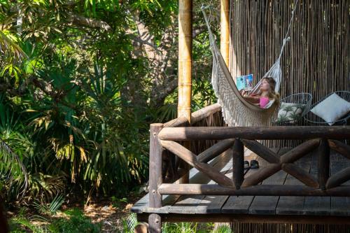 a girl sitting in a hammock on a porch at Isla Fuerte Eco House in Puerto Limón