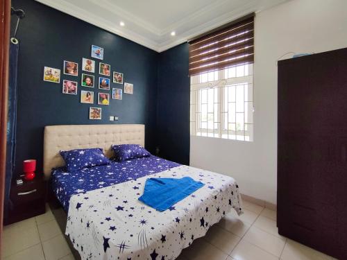um quarto com uma cama com uma parede azul em Mawolè em Cotonou