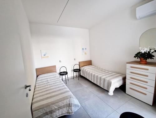 a bedroom with a bed and a dresser and chairs at Dainese Apartments, Casa Miriam in Lido di Jesolo