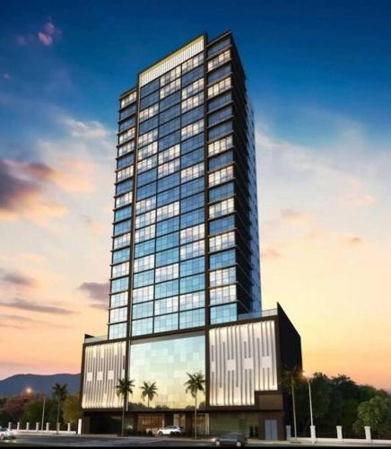a tall glass building with palm trees in front of it at Infinity Tower Flat - 1403 in Itapema