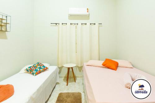 two beds in a room with a heater and a table at Pousada Cantos do Cerrado in Chapada dos Guimarães
