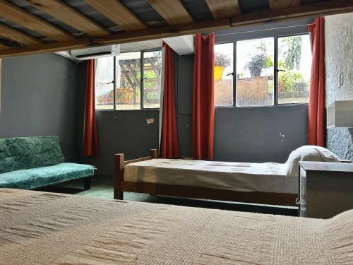 a bedroom with two beds and a chair and windows at Hostel Bohemian House in Montevideo