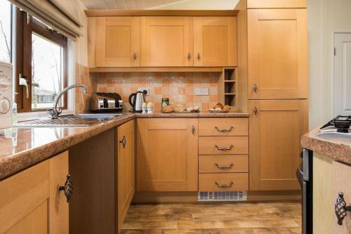 a kitchen with wooden cabinets and a sink at Luxury 3 bedroom lodge with free in lodge wifi in Carnforth