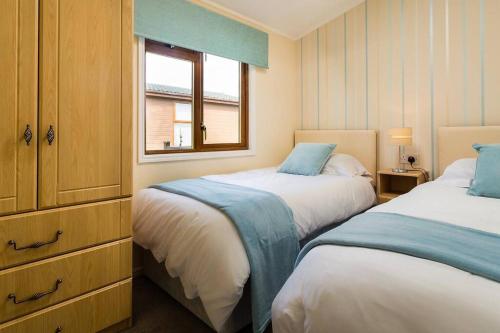 a bedroom with two beds and a window at Luxury 3 bedroom lodge with free in lodge wifi in Carnforth
