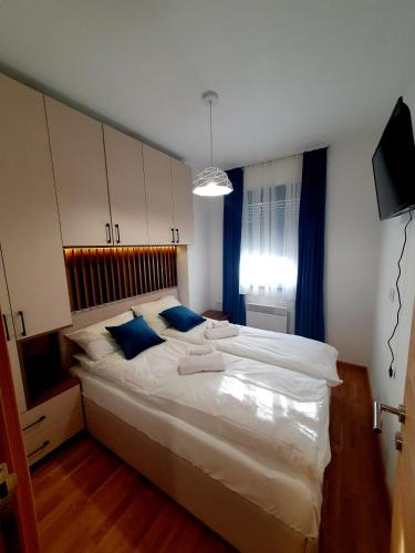 a bedroom with a large white bed with blue pillows at Apartman Felicita 2 in Zlatibor