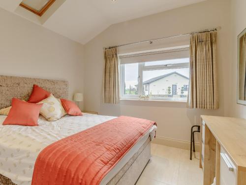 een slaapkamer met een bed met oranje kussens en een raam bij Sunnyside Shreyas in Wilpshire