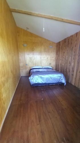 a bed in a room with a wooden floor at Cabañas tunquelen in Osorno