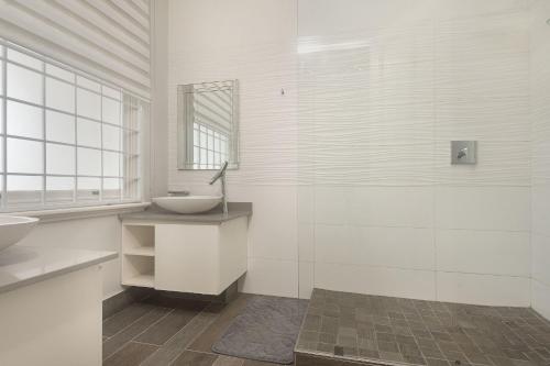 a white bathroom with two sinks and a window at Beach Haven Townhouse in Durban