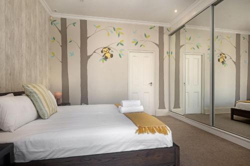 a bedroom with a bed with trees on the wall at Beach Haven Townhouse in Durban