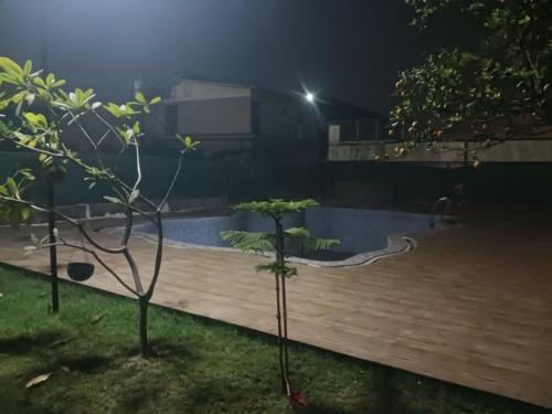 un patio trasero por la noche con piscina en Sun n moon farm, en Noida