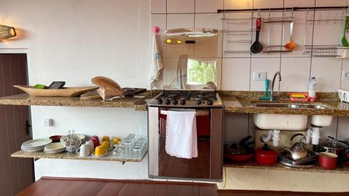 a kitchen with a stove top oven next to a sink at Casa com vista a praia da Barra do Sahy in Barra do Sahy