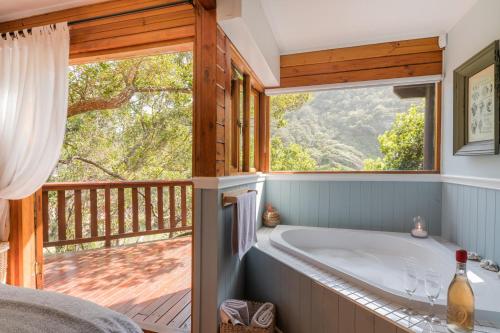 a bathroom with a tub and a large window at Ballots Bay Treehouse by Host Agents in George