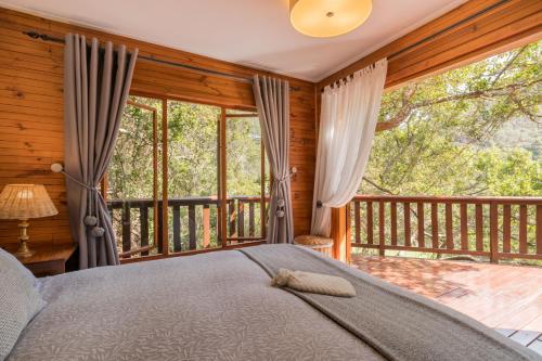 a bedroom with a bed and a balcony at Ballots Bay Treehouse by HostAgents in George