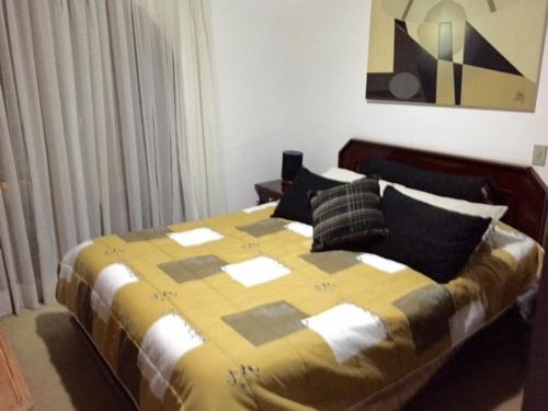 a bedroom with a large bed with a yellow blanket at Alto do Capivari in Campos do Jordão