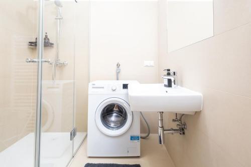 ein Badezimmer mit einer Waschmaschine und einem Waschbecken in der Unterkunft Family Apartment in Wien