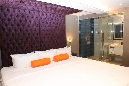a bedroom with a large white bed with orange pillows at BLVD Hotel and Studios Universal-Hollywood, an Ascend Collection Hotel in Los Angeles