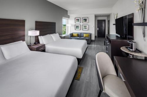 a hotel room with two beds and a living room at DoubleTree by Hilton Sarasota Bradenton Airport in Sarasota