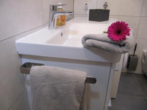 La salle de bains est pourvue d'un lavabo avec une fleur rose. dans l'établissement Sperrentalblick, à Sankt-Andreasberg