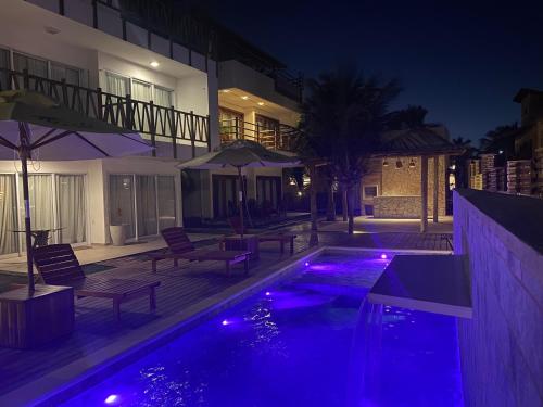 a swimming pool with purple lights in front of a house at Bali BG Casa Bamboo in Barra Grande
