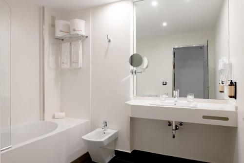 uma casa de banho branca com um lavatório e um WC em Hotel Infanta Leonor em Écija