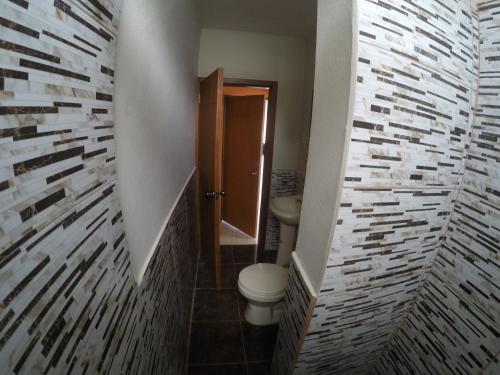 een kleine badkamer met een toilet en een bakstenen muur bij Estancia Spondylus in San Lorenzo