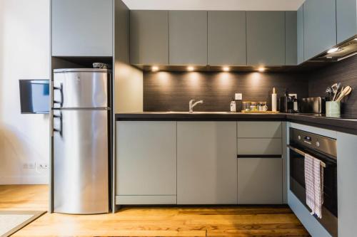 een keuken met witte kasten en een roestvrijstalen koelkast bij MAITALEA KEYWEEK Quiet downtown apartment in Biarritz