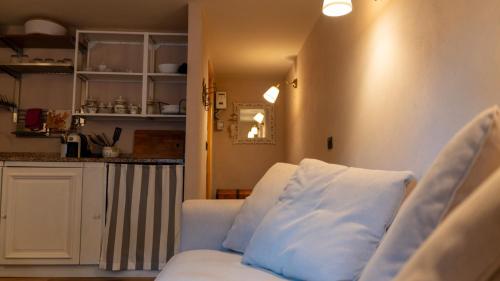 ein Wohnzimmer mit einem weißen Sofa und einer Küche in der Unterkunft Bilocale a due passi dal mare immerso nel verde in Castiglioncello