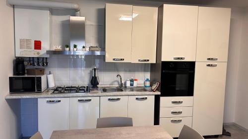 een keuken met witte kasten, een wastafel en een magnetron bij Da Serena in Tarcento