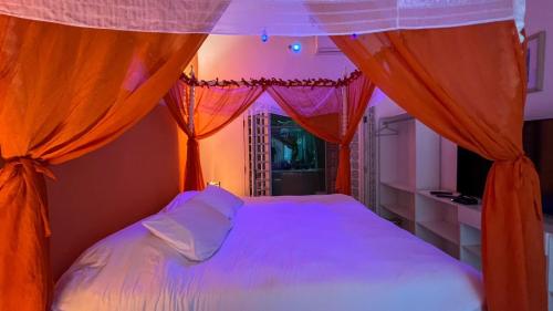 Schlafzimmer mit einem Bett mit orangefarbenen Vorhängen in der Unterkunft Casa com vista a praia da Barra do Sahy in Barra do Sahy