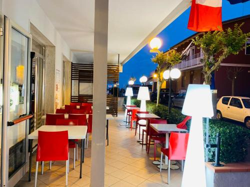 un restaurante con sillas rojas y mesas en un edificio en hotel roby, en Rímini