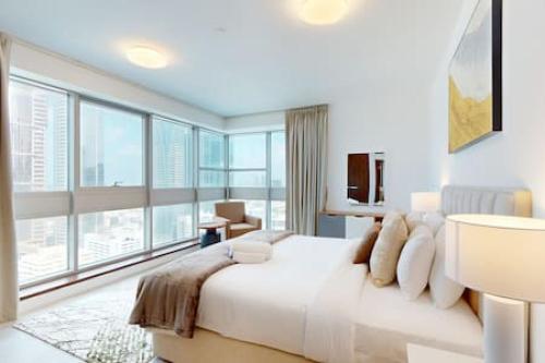 a bedroom with a large bed and large windows at West Heights 1 - Vacationer in Dubai