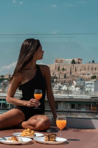 a woman sitting on a table with a glass of wine at Athesense Suites in Athens