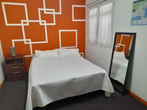 1 dormitorio con 1 cama con pared de color naranja en Hospedajes Mary en Ushuaia