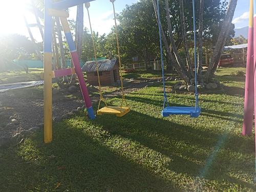 a swing set in a yard with the sun shining at Hotel Rancho El Vergel in Montenegro