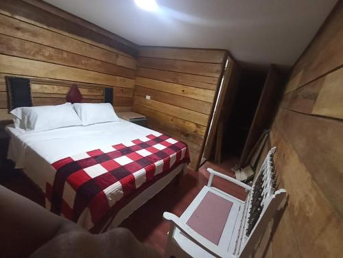 a small bedroom with a bed and a chair at Hotel Rancho El Vergel in Montenegro