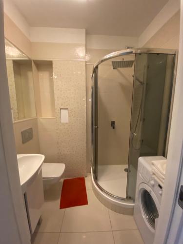 y baño con ducha, lavabo y lavadora. en Glamour Residence, en Varsovia