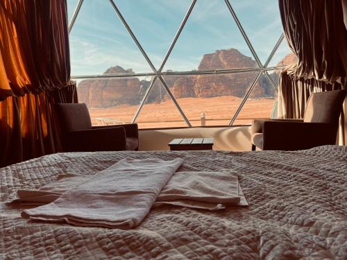 a bed in a room with a view of the desert at RUM HiLTON lUXURY CAMP in Wadi Rum