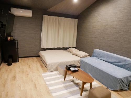 niewielka sypialnia z łóżkiem i kanapą w obiekcie HOOD - Vacation STAY 46032v w mieście Amami