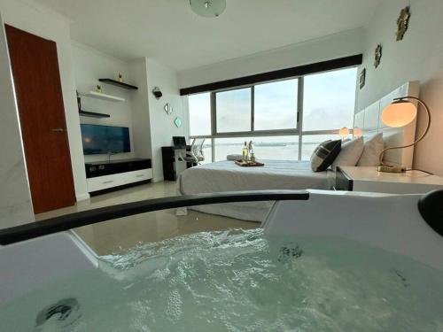 a room with a tub with a bed and a television at Ecusuites vista Río Jacuzzi Privado Wyndham 802 in Guayaquil