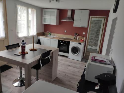 une cuisine avec une table et une cuisine avec un lave-linge dans l'établissement Maison calme et chaleureuse, à Léré