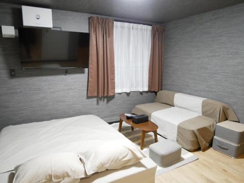 a bedroom with a bed and a couch and a tv at HOOD - Vacation STAY 46466v in Amami