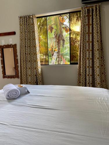 a bedroom with a white bed with a large window at HOSTAL LOS NOGALES in Aguaytía