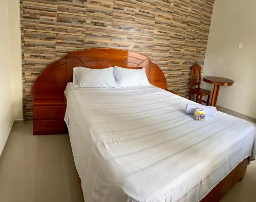 a bedroom with a large bed with a wooden headboard at HOSTAL LOS NOGALES in Aguaytía