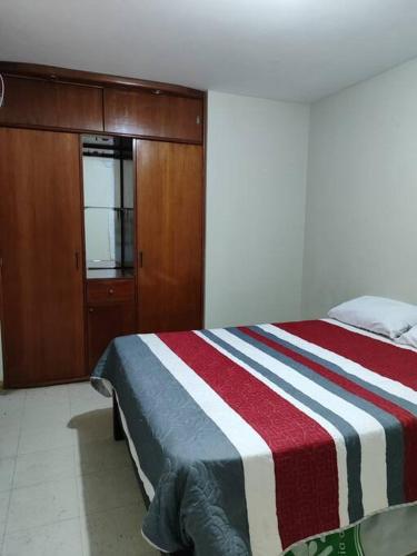 a bedroom with a bed with a red and white striped blanket at Departamento 4 camas 3 hab in Tacna