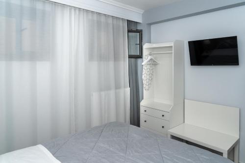 une chambre blanche avec un lit et une télévision dans l'établissement Crystal Apartment with free private parking of stayinthess, à Thessalonique