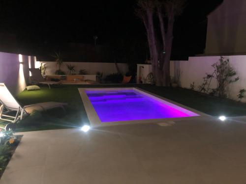 - une piscine éclairée la nuit avec des lumières violettes dans l'établissement Maison avec jardin et piscine, à Marseille