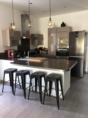 une cuisine avec une grande île avec quatre tabourets dans l'établissement Maison avec jardin et piscine, à Marseille